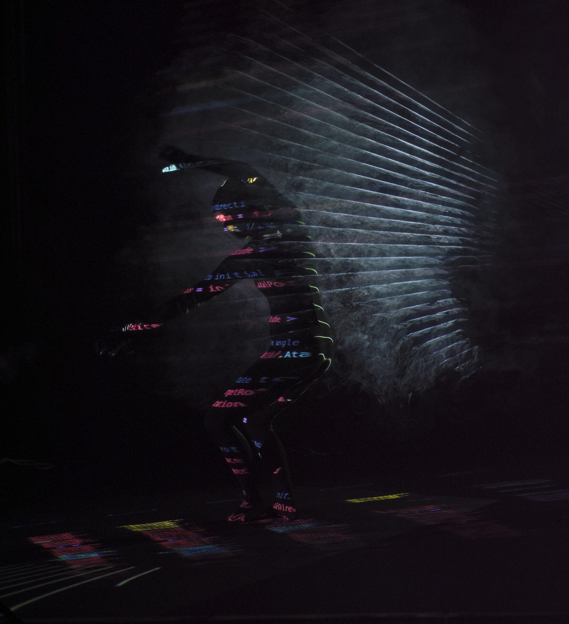 A dancer in darkness with geometric light projected across her body and the space behind her